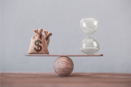 A scale balancing money and an hourglass