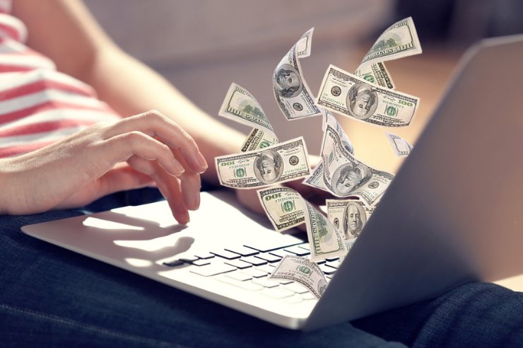 Hundred dollar bills flying out of a laptop