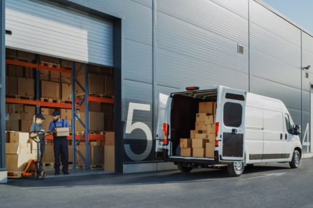 A van being loaded with packages outside of a warehouse