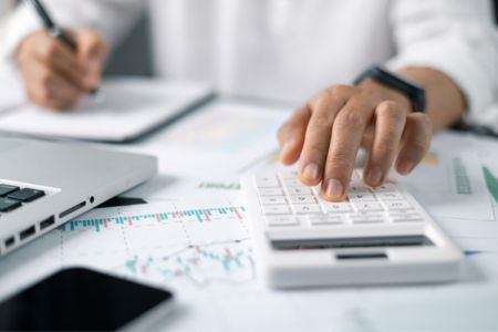 Person at desk with calculator and computer