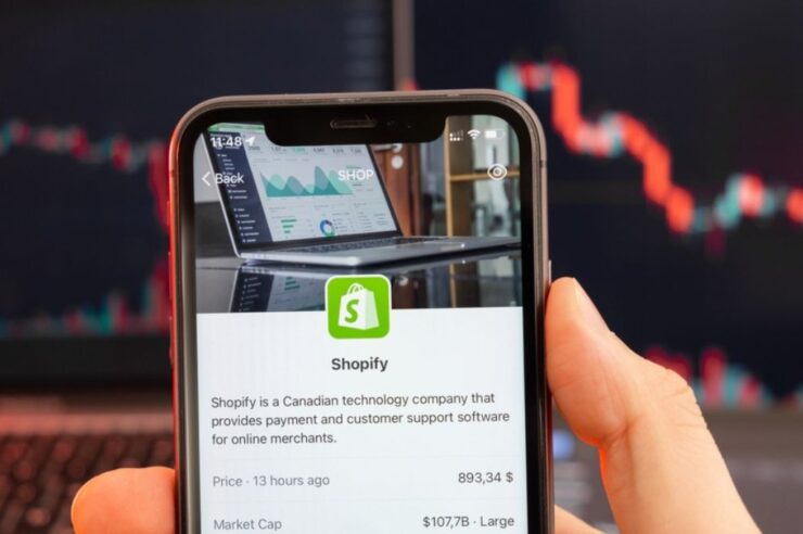 A hand holding a smartphone with the shopify app open