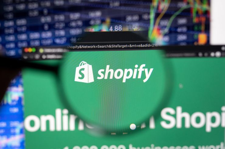 Shopify logo on computer screen under magnifying glass.